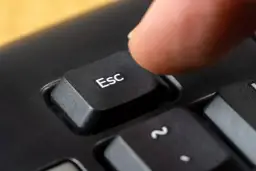 Palec naciska klawisz Esc, symbolizując zakończenie działalności gospodarczej.