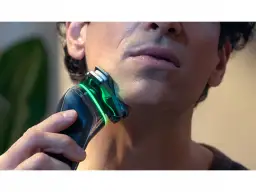 Mężczyzna goli twarz golarką Philips z zielonym podświetleniem.