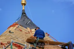 Cieśla dekarz pracuje na dachu, montując drewniane pokrycie.