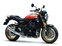 Stylowy czarny motocykl Kawasaki Z900RS z pomarańczowo-żółtym malowaniem na baku i złotymi felgami.