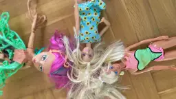 Trzy lalki leżą na podłodze. Jedna ma różowe włosy, druga blond, a trzecia sukienkę w słoneczniki. Dowiedz się, jak rozczesać włosy lalce, by wyglądała jak nowa!
