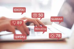 Dłonie piszą na klawiaturze, otoczone dymkami z obraźliwymi komentarzami: "IDIOTA!", "SŁABIAK", "PRZEGRYW", "!-@#$@". To przykład naruszenia dóbr osobistych w sieci.