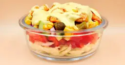 Sałatka gyros w szklanej misce z kurczakiem, kukurydzą, ogórkiem i sosem.