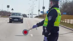 Policjant w kamizelce odblaskowej kieruje ruchem, zatrzymując audi. Nie ma tu fotoradaru, ale kontrola drogowa trwa.