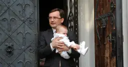 Mężczyzna w garniturze trzyma dziecko. Czy to jedno z dzieci Ziobry?