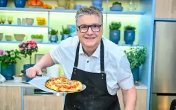 Uśmiechnięty kucharz prezentuje pyszną pizzę rzymską prosto z pieca.