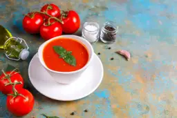 Zupa pomidorowa z bazylią, pomidory, oliwa, sól, pieprz i czosnek na kolorowym tle.