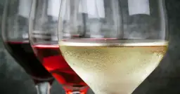 Trzy kieliszki z winem: czerwonym, różowym i białym. Czy przyczyny bólu głowy po winie to siarczyny czy taniny?