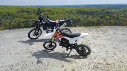 Dwa motocykle crossowe na tle lasu. Czy crossem można jeździć po ulicy? Te maszyny są stworzone do terenu.