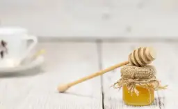 Słodki miód w słoiczku z drewnianą chochlą. Zastanawiasz się, ile kcal ma łyżeczka miodu?