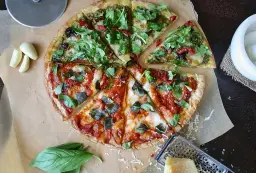 Dwie połówki pizzy: jedna z pesto i rukolą, druga z sosem pomidorowym i bazylią. Zastanawiasz się, ile kosztuje pizza w Czechach?