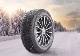 Opona zimowa Michelin X-Ice Snow 215/55R17 na tle zaśnieżonego lasu. Sprawdź nasz ranking opon zimowych!