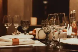 Table dressée avec verres à vin, serviette et bouteille d'eau.