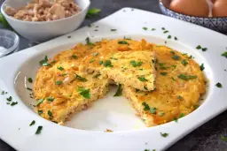 Tortilla de atún dorada y esponjosa, espolvoreada con perejil fresco. Un plato sencillo y delicioso.
