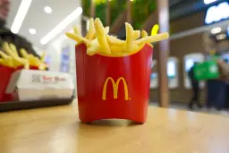 Czerwone pudełko z frytkami McDonald's na drewnianym stole.