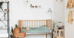 Urocze **ściany w pokoju dziecięcym** zdobią pluszowe misie i drewniane zabawki. Drewniane łóżeczko z zieloną pościelą i wiklinowy kosz tworzą przytulną atmosferę.