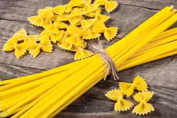 Makaron z mąki durum i zwykłej pszennej. Farfalle i spaghetti na drewnianym tle.