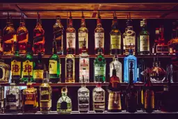 Rzędy butelek z whisky i innymi alkoholami. Zastanawiasz się, ile kropel wody dodać do whisky, by "otworzyć" jej aromat i smak?