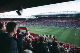 Kibice na stadionie z szalikami, czekają na wznowienie gry. Zastanawiają się, ile trwa przerwa w meczu.