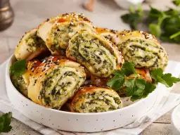 Pyszne przekąski z ciasta do pizzy ze szpinakiem i serem, posypane sezamem. Idealne na imprezę!