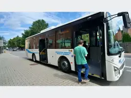 Autobus miejski z otwartymi drzwiami, wsiada pasażer.