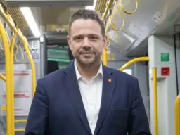 Rafał Trzaskowski, prezydent Warszawy, w środkach komunikacji miejskiej. Jego życiorys to historia zaangażowania w rozwój stolicy.