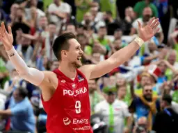 Bartosz Szczepanik w koszulce z numerem 9, z podniesionymi rękami, świętuje zwycięstwo na tle rozentuzjazmowanych kibiców.