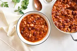 Aromaticzna zupa meksykańska z kurczakiem, pełna fasoli i mielonego mięsa, podana w misce i garnku.