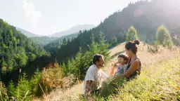 Rodzina odpoczywa na trawie, podziwiając najpiękniejsze szlaki w Beskidach.