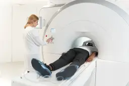 Pacjent leży w aparacie MRI, a technik kontroluje badanie. Choć rezonans magnetyczny jest bezpieczny, warto znać potencjalne skutki uboczne.