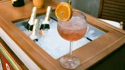 Orzeźwiający drink z pomarańczą i lodem, obok schłodzone butelki, idealne na aperitivo. Zastanawiasz się, jakie prosecco do Aperola?