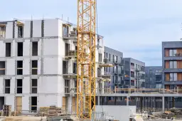 Budowa osiedla mieszkaniowego z żurawiem budowlanym i nowymi budynkami.