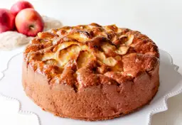 Bizcocho de manzana casero, dorado y jugoso, con trozos de manzana caramelizada en la superficie.