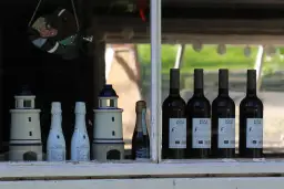 Witrażowa rybka wisi nad butelkami wina i latarniami morskimi. Jak sprawdzić rocznik wina, kiedy starsze nie zawsze oznacza lepsze?