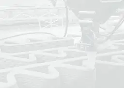 Drukarka 3D buduje strukturę z szarego materiału, tworząc faliste linie.