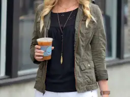 Chica con chaqueta verde militar y café helado.