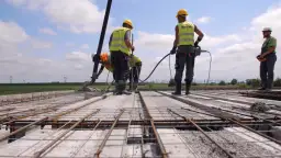 Budowa stropu: pracownicy wylewają beton, używając pompy. Jaki beton na strop? Ten, który zapewni trwałość konstrukcji.