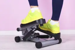 Osoba w neonowych butach ćwiczy na stepperze.