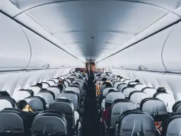 Wnętrze samolotu Wizz Air, rzędy siedzeń wypełnione pasażerami. Wizz Priority zapewnia komfortową podróż.