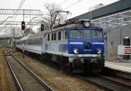 Niebieska lokomotywa EU07-067 PKP Intercity stoi na torach. Co oznacza TLK w pociągach? To oznaczenie tanich połączeń PKP Intercity.