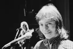 Chris Norman z mikrofonem na scenie, w tle inny muzyk.