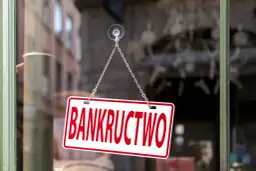Tabliczka "BANKRUCTWO" wisząca na łańcuszku na szybie.