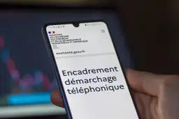 Un smartphone affiche le site du Ministère de l'Économie, avec le titre "Encadrement démarchage téléphonique".