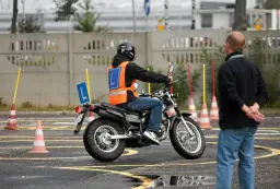Nauka jazdy na motorowerze na placu manewrowym. Czy to szansa na prawo jazdy AM za darmo? Instruktor obserwuje kursanta.