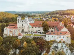 Najstarszy klasztor w Polsce, benedyktyńskie opactwo na skale, otoczone jesiennymi drzewami.