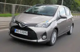 Szary Toyota Yaris w ruchu drogowym, widok z przodu.
