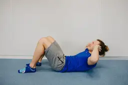 Ćwiczenia na brzuch, które pomogą Ci ujędrnić brzuch. Mężczyzna wykonuje brzuszki na niebieskiej macie.