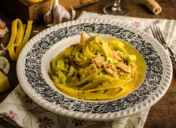 Talerz z makaronem tagliatelle w kremowym sosie z kawałkami mięsa i szczypiorkiem.