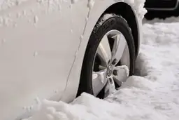 Biały samochód z felgami i oponami Michelin w śniegu. Zastanawiasz się, jakie opony zimowe wybrać?