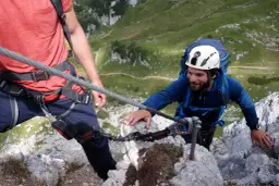 Wspinaczka po via ferrata to przygoda! Dwóch mężczyzn pokonuje skalną trasę, zabezpieczonych linami.